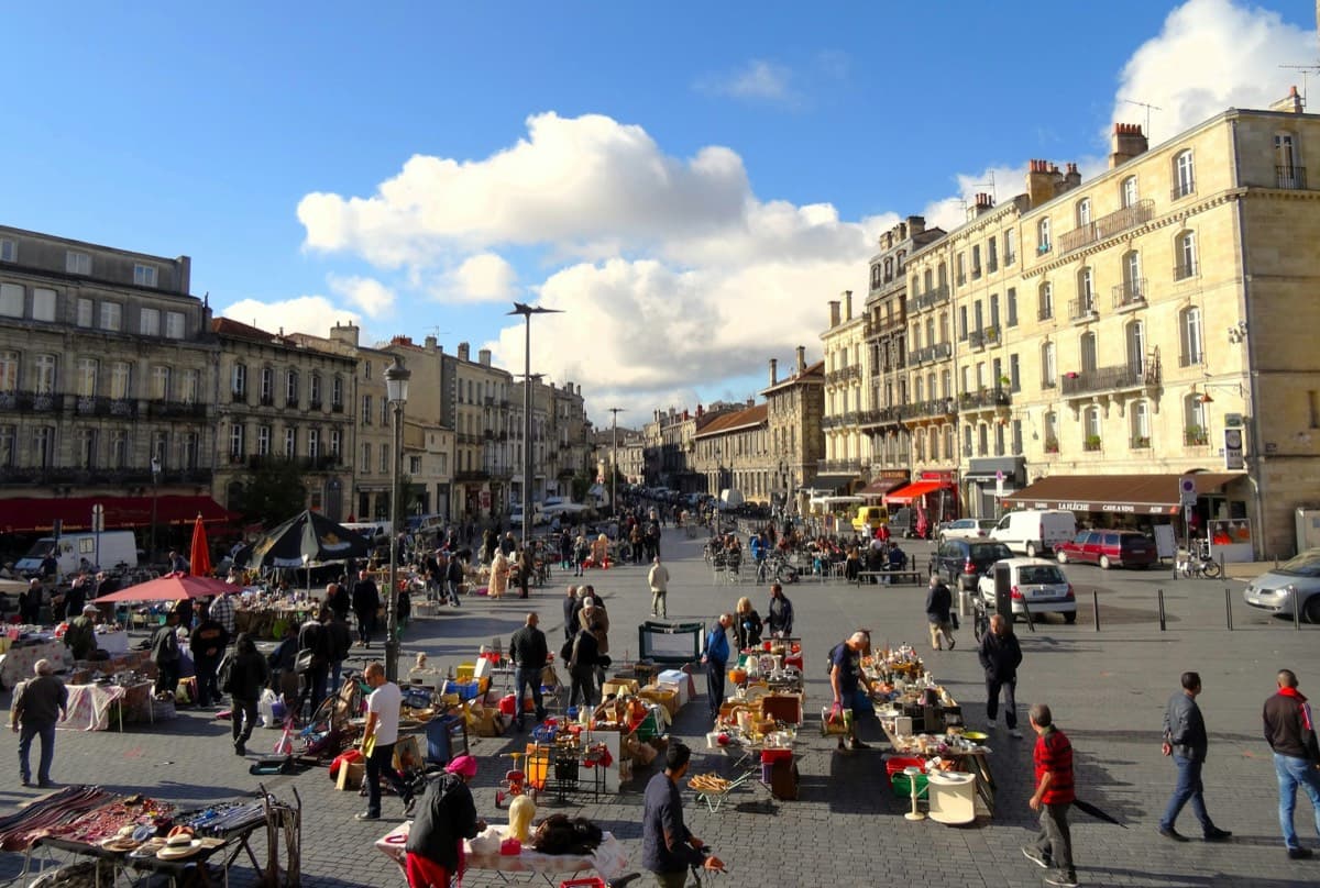 Vendeur souriant derrière son stand de brocante bien achalandé